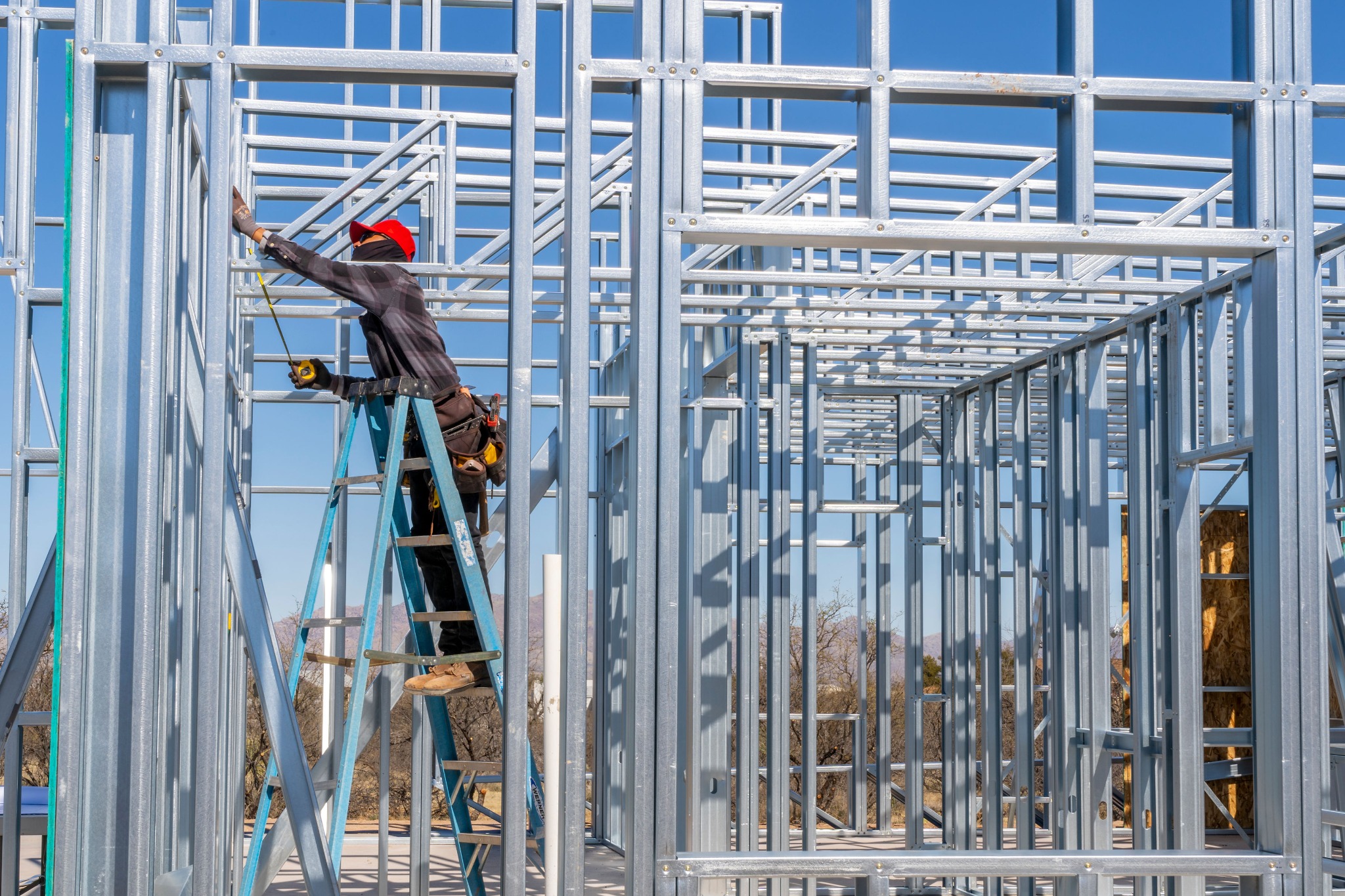 A worker assembling cold-formed steel framing inside a home under construction.