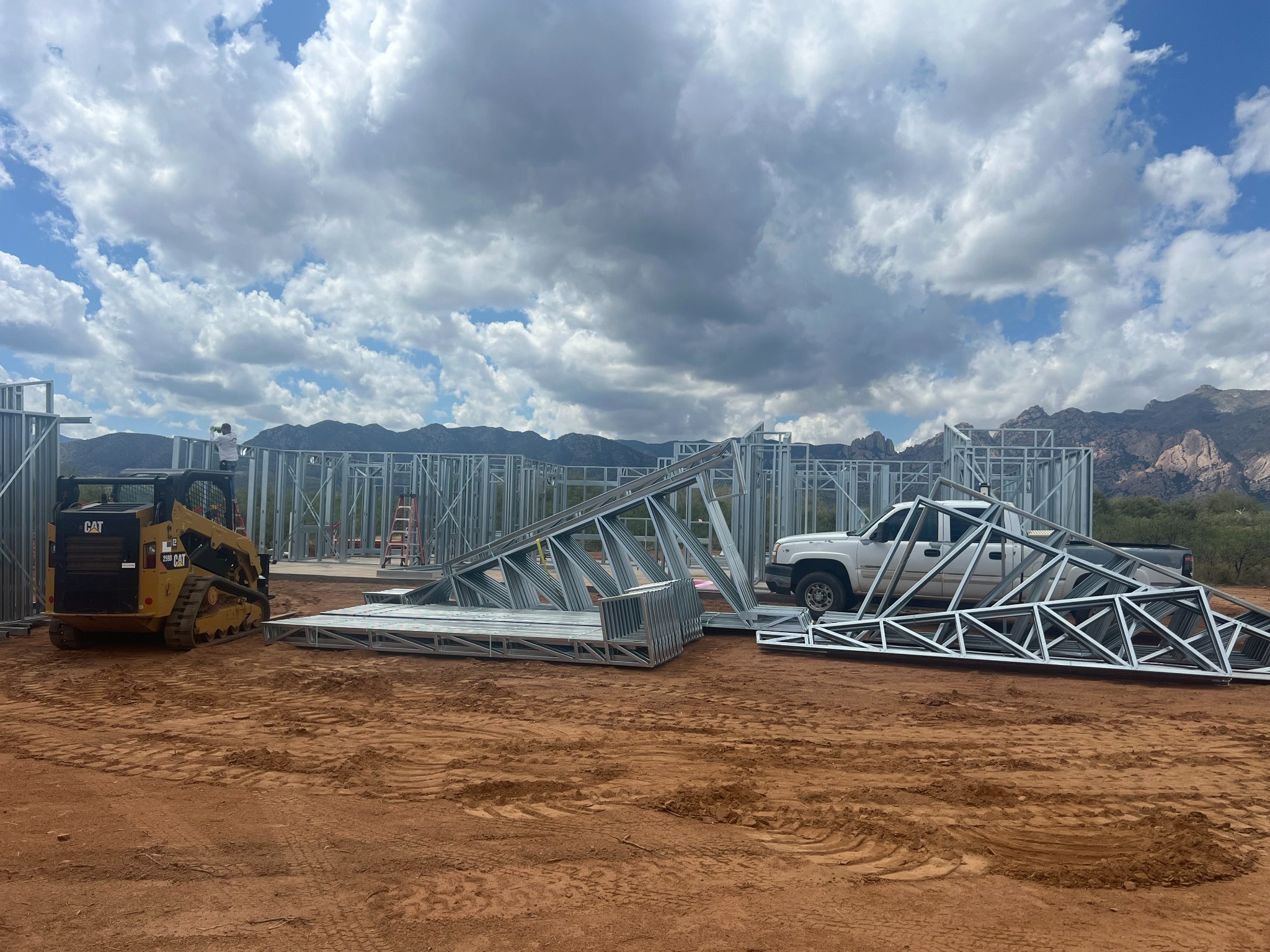 Steel roof trusses staged beside a home construction site.