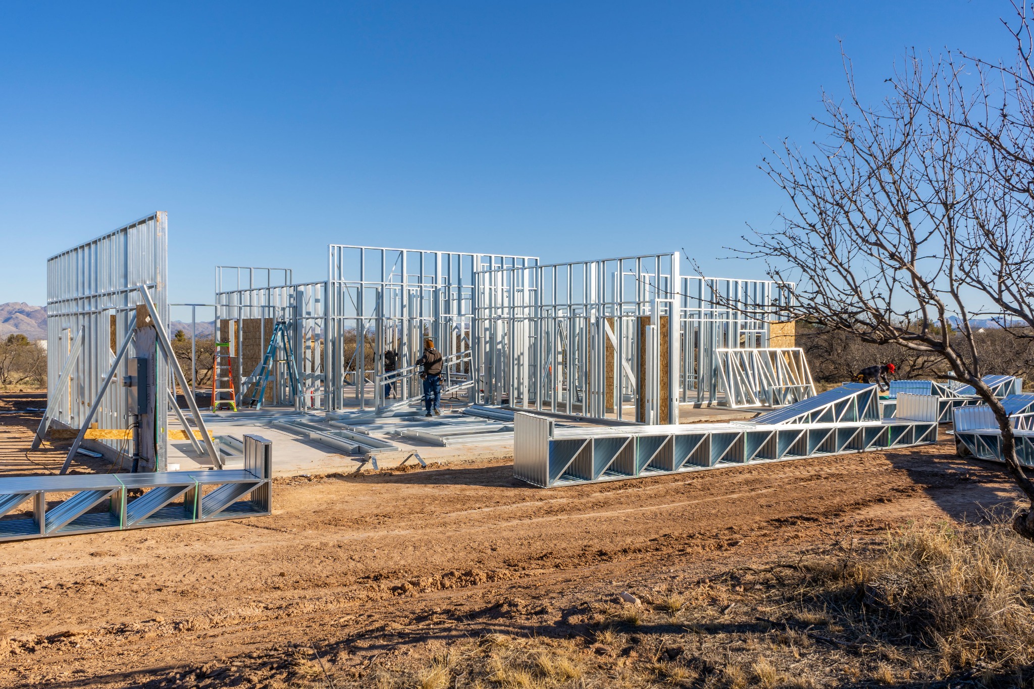 Steel wall frames and roof components at a residential construction site.