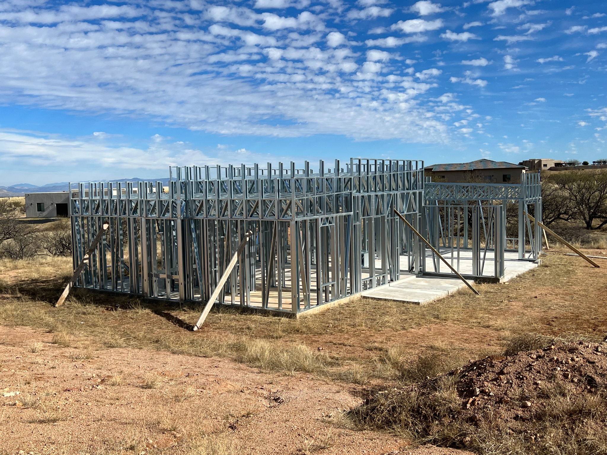 Cold-formed steel home framing on a foundation in the Arizona landscape.