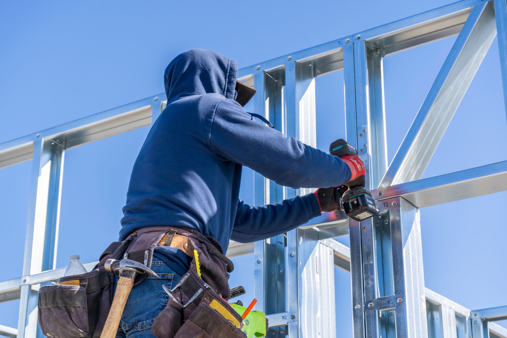 A builder fastening a connection in a cold-formed steel structure.